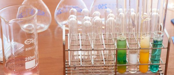 化学实验室中烧瓶内发生剧烈化学反应，绿色荧光液体翻腾冒泡，实验台整洁专业，科学感强烈